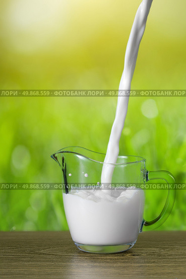 Milk pouring into the glass on nature background. Стоковое фото, агентство Ingram Publishing / Фотобанк Лори