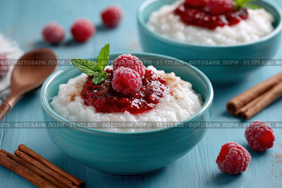 Milky Rice pudding with superberries and red raspberry sauce, served in a white bowl on blue tablecloth background. Rice porridge topped with some raspberries and cinnamon sprinkled. Old English style. Стоковое AI-изображение, AI-художник Марина Демидюк / Фотобанк Лори
