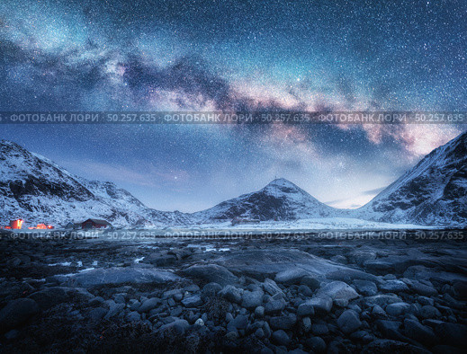 Milky Way above snow covered mountains and stone beach in winter at night in Lofoten Islands, Norway. Arctic landscape with blue starry sky,  sea coast, snowy rocks, galaxy. Beautiful space and nature. Стоковое фото, агентство Ingram Publishing / Фотобанк Лори