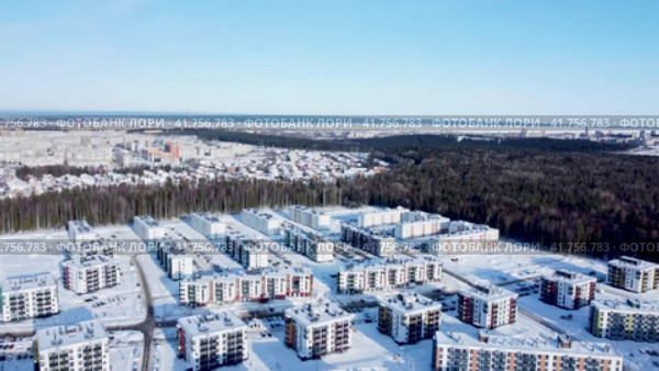 Многоквартирные жилые дома в спальном районе Древлянка-7, в городе Петрозаводске в солнечный зимний день. Панорама зимнего города. Аэросъемка, панорамный вид пролетом в сторону (2023 год). Редакционное видео, видеограф Sergei Gorin / Фотобанк Лори