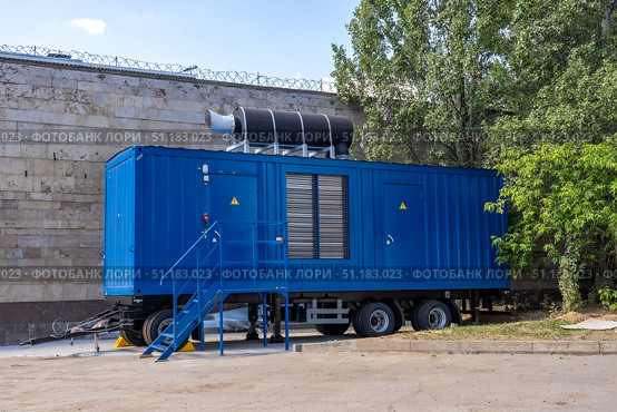 Modern blue diesel powered emergency backup electric generator on portable trailer. Standby backup generator power. Industrial mobile diesel generator for office building, connected to electrical network by cable. Offshore container trailer with powerful electric generator. Стоковое фото, фотограф Данила Большаков / Фотобанк Лори