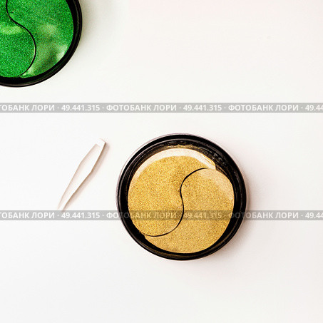 Modern cosmetic concept. Golden and green facial eye patches in jar with tweezers. Hydrogel patch.  Anti aging and lifting . Face skin care. Hydrating and wrinkles patch. Top view with copy space. Стоковое фото, агентство Ingram Publishing / Фотобанк Лори