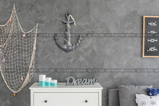 Modern ocean inspired  interior with white commode, fishing net and anchor hanging on the wall. Стоковое фото, агентство Ingram Publishing / Фотобанк Лори
