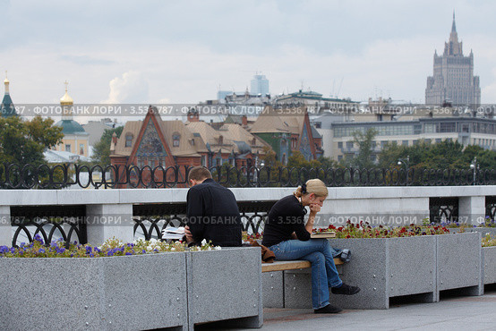 Молодая пара читает на уличной скамейке (2009 год). Редакционное фото, фотограф Юрий Синицын / Фотобанк Лори