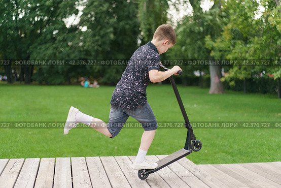 Moscow, Russia - July 26-2019 Trick at sportive push scooter in the park. Редакционное фото, фотограф YuryKara / Фотобанк Лори
