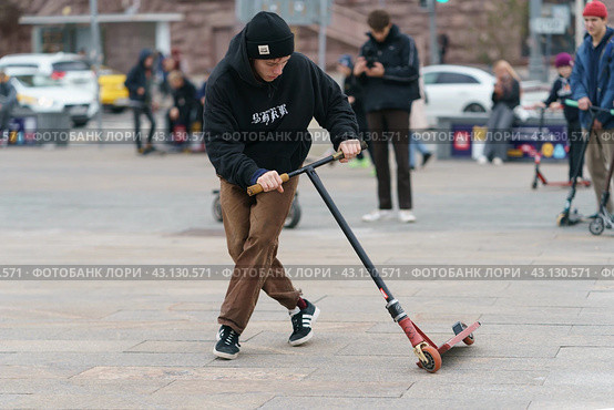 Moscow, Russia - October 2, 2021: Successful push scooter stunt on the street in autumn day. Boy did the trick. Street Jam. He didn't fell. Extreme sports is popular among youth. Редакционное фото, фотограф YuryKara / Фотобанк Лори