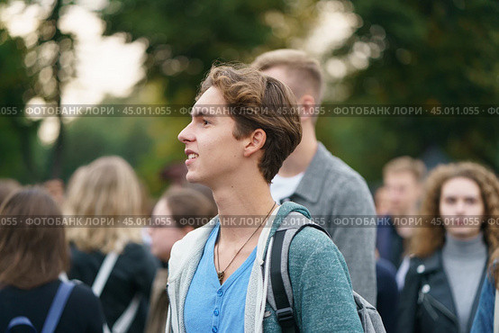 Moscow, Russia - September 5, 2019: Portrait of young man visiting the city festival in the Gorky park. A crowd of youth around him. Blurred background. Редакционное фото, фотограф YuryKara / Фотобанк Лори