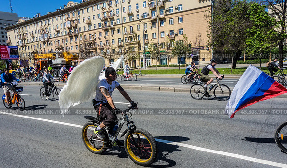 Московский весенний велофестиваль (2024). Парень с белыми крыльями ангела едет на велосипеде./ Moscow spring cycling festival. A guy with white angel wings rides a bicycle. Редакционное фото, фотограф Iva Noel / Фотобанк Лори