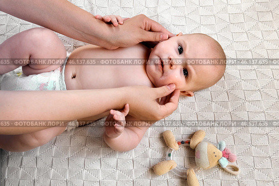 Mother Massaging and Lubricates Baby Face Gently. Mom Applying Cream or Oil on Her Child's Face. Happy Newborn Baby Smiling. Neonate Toddler at Cozy Home Space. Skin Care, Baby Development Concept. Стоковое фото, фотограф Марина Демидюк / Фотобанк Лори
