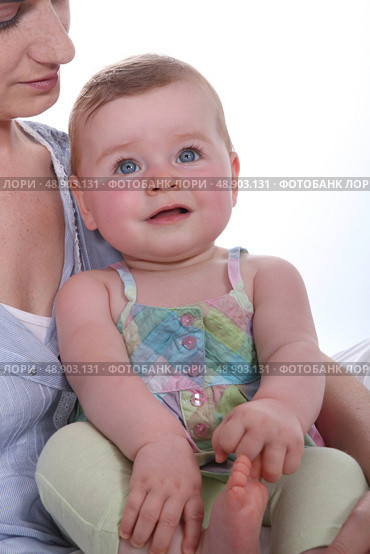 Mother resting baby daughter on knee. Стоковое фото, агентство Ingram Publishing / Фотобанк Лори