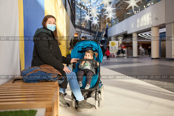 Mother resting with her child sitting in children pram, family walking in shopping center, adult woman wearing face mask, copyspace. Стоковое фото, фотограф Кекяляйнен Андрей / Фотобанк Лори
