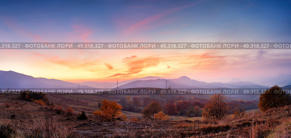 Mountain autumn panoramic landscape with colorful forest. Panorama of sunset in a Carpathian mountain valley with wonderful gold light on a hills. Panoramic image of rural fields in evening light. Стоковое фото, агентство Ingram Publishing / Фотобанк Лори