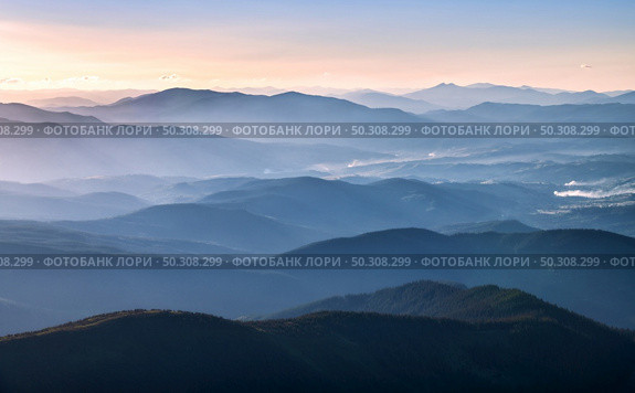 Mountains lighted by bright sunbeams at sunset in autumn. Landscape with mountain ridges in fog, rocks, forest, colorful sky with orange sunlight in fall. Aerial view of mountain valley. Top view. Стоковое фото, агентство Ingram Publishing / Фотобанк Лори