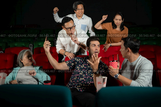 Movie etiquette, Do not talk on the phone while in the cinema, Group recreation and entertainment concept. Стоковое фото, агентство Ingram Publishing / Фотобанк Лори