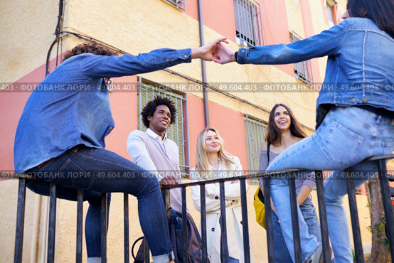 Multi-ethnic group of friends gathered in the street leaning on a railing. Young people having fun together.. Multi-ethnic group of friends gathered in the street leaning on a railing. Стоковое фото, агентство Ingram Publishing / Фотобанк Лори