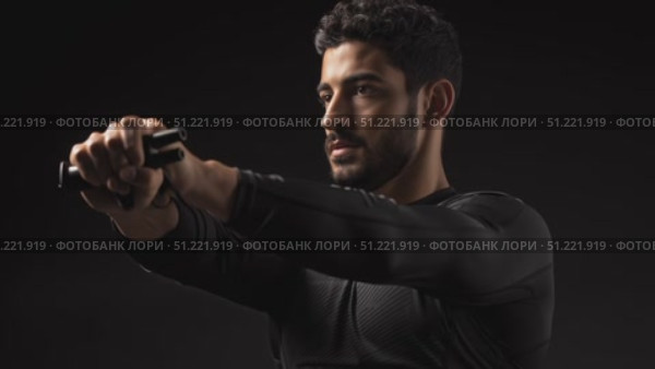 Muscular athlete pulling resistance band across chest, gripping tightly with both hands, displaying powerful fitness movement against dark background. Стоковое AI-видео, аниматор Юрий Поздников / Фотобанк Лори