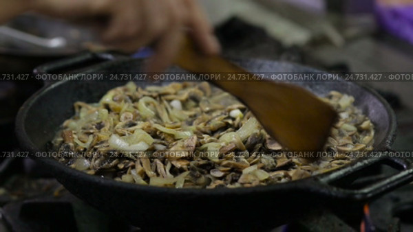 Mushrooms are fried in a wok in the kitchen. Стоковое видео, видеограф Загородний Кирилл / Фотобанк Лори