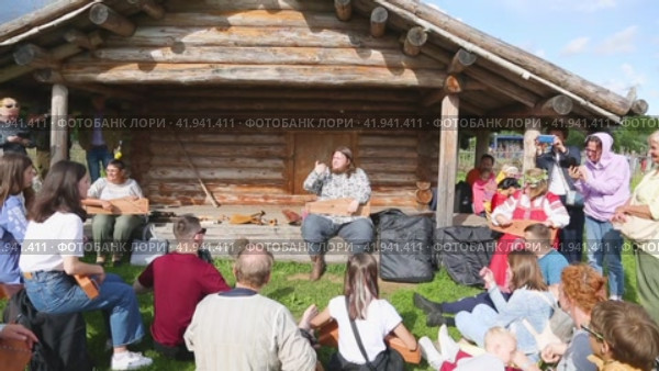 Musician in russian clothing teaches spectators to playing on ancient musical instrument gusli (harp) (2024 год). Редакционное видео, видеограф FotograFF / Фотобанк Лори