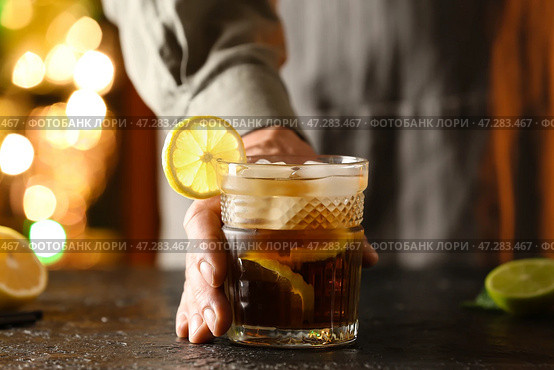 Мужчина-бармен со стаканом вкусного коктейля Cuba Libre на столе в баре. Стоковое фото, фотограф Pixel_shot / Фотобанк Лори