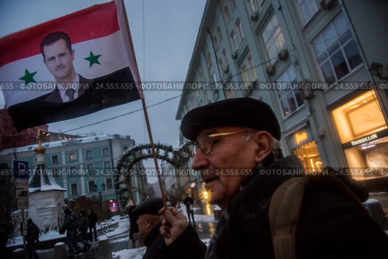 Мужчина держит флаг Сирии с портретом президента Башара Асада на митинге-шествии коммунистов в городе Москве, Россия (2016 год). Редакционное фото, фотограф Николай Винокуров / Фотобанк Лори