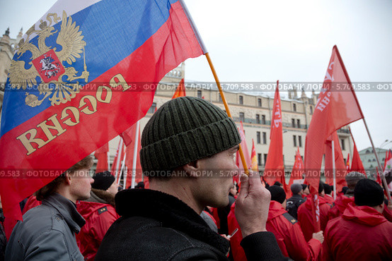 Мужчина держит российский триколор на митинге "В поддержку Крыма и против фашизма" на площади Революции города Москвы 15 марта 2014. Редакционное фото, фотограф Николай Винокуров / Фотобанк Лори