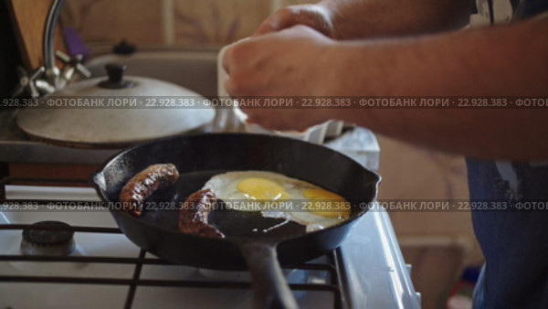 Мужчина готовит глазунью с сосисками на кухне. Стоковое видео, видеограф Константин Колосов / Фотобанк Лори