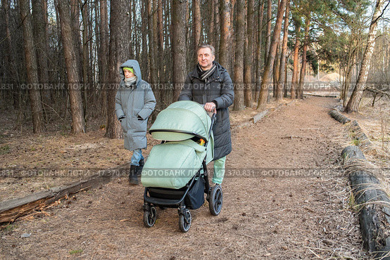мужчина гуляет с детьми в парке. отец разговаривает с сыном-подростком, толкает коляску с младшим ребенком, гуляет в парке весной. Стоковое фото, фотограф Яна Проничева / Фотобанк Лори