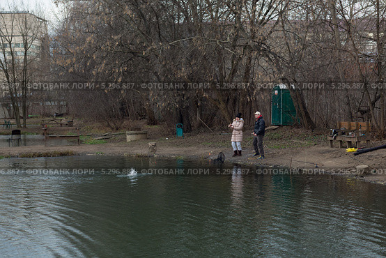Мужчина и женщина на пруду вываживают пойманную рыбу. Стоковое фото, фотограф Михаил Иванов / Фотобанк Лори