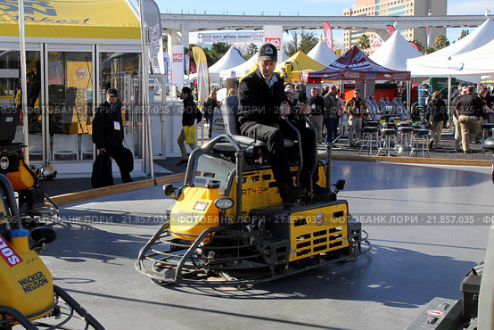 Мужчина тестирует двухроторную затирочную машину Wacker Neuson CRT 48 на залитом бетоне на выставке World of Concrete 2016. Редакционное фото, фотограф Роман Коротков / Фотобанк Лори