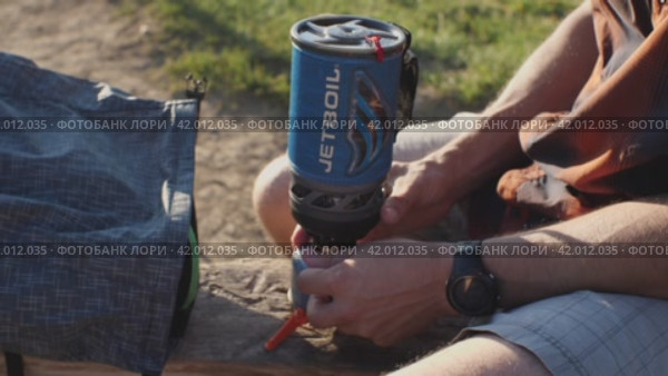 Мужчина зажигает газовую горелку Jetboil. Концепция приготовления пищи на природе. Гузерипль, Республика Адыгея, Россия 19 июля 2021 года. Редакционное видео, видеограф Воловодов Владимир / Фотобанк Лори