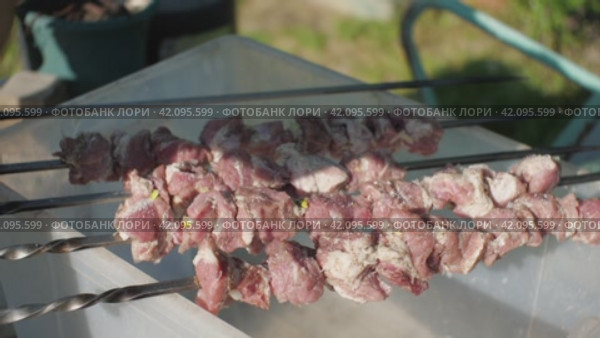 Мужская рука посыпает солью сырой шашлык, нанизанный на шампуры. Замедленная съемка. Крупный план. Стоковое видео, видеограф Воловодов Владимир / Фотобанк Лори