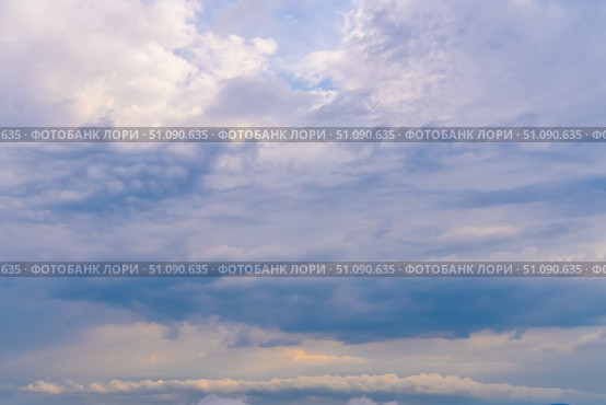 Mysterious clouds drift across a light blue sky at dusk revealing hints of sunlight and fantastic formations. Стоковое фото, фотограф Владимир Разгуляев / Фотобанк Лори