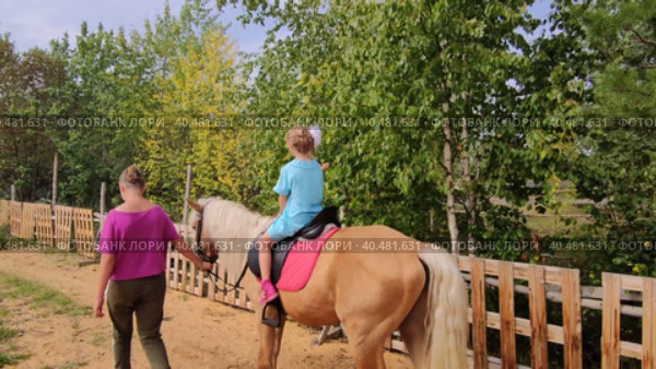 На улице в прекрасный теплый день девочка катается на лошади. Outside on a beautiful warm day, a girl rides a horse. Редакционное видео, видеограф Мария / Фотобанк Лори