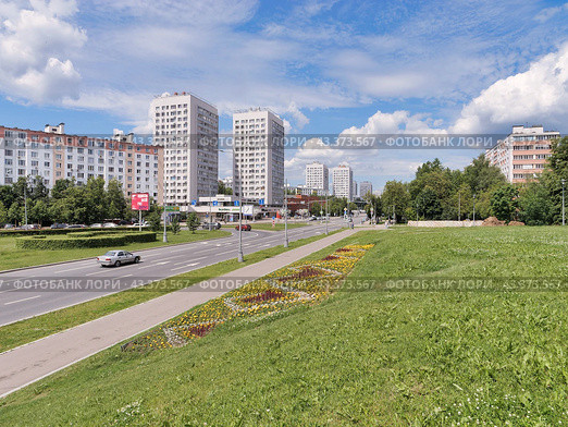 Начало Центрального проспекта в подмосковном Зеленограде. Клумба с цветами. Дорога с проезжающим автомобилем. Голубое небо с белыми облаками. (2024 год). Стоковое фото, фотограф Сергей Никифоров-Гордеев / Фотобанк Лори