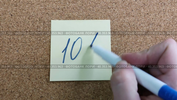 Надпись 10% на бумажном стикере приклеенном к пробковой  доске. Женщина пишет маркером на желтой бумаге. Синий фломастер в женской руке. Рукописный текст красивым почерком. Процент скидки или прибыли. Inscriptionis 10% on paper sticker glued to cork board. Woman writes with marker on yellow paper. Blue felt-tip pen in woman hand. Handwritten text in beautiful handwriting. Percentage of discount or profit. Стоковое видео, видеограф Ирина / Фотобанк Лори