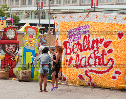 Надпись "Berlin lacht"  и разговаривающие девушки летним днем на Александрплатц в Берлине (2015 год). Редакционное фото, фотограф Наталья Николаева / Фотобанк Лори