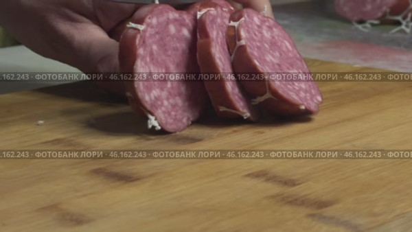 Нарезка варено-копченой колбасы крупными кусками на деревянной доске. Стоковое видео, видеограф Ярославский Максим / Фотобанк Лори