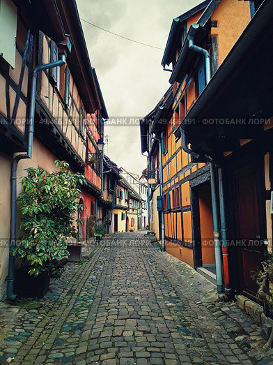 Narrow streets of the old Eguisheim village with half-timbered medieval houses along the famous wine route in Alsace, France. Стоковое фото, агентство Ingram Publishing / Фотобанк Лори