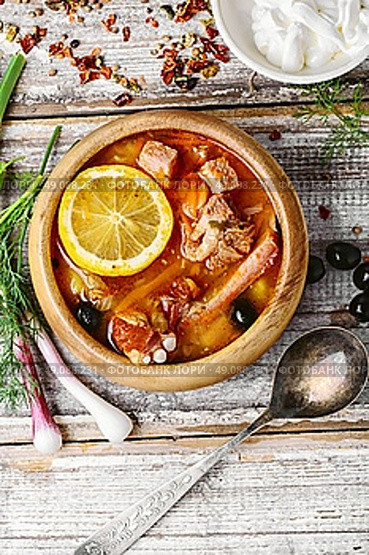 National Ukrainian soup Solyanka. Traditional solyanka with smoked meats in wooden plate. Стоковое фото, агентство Ingram Publishing / Фотобанк Лори