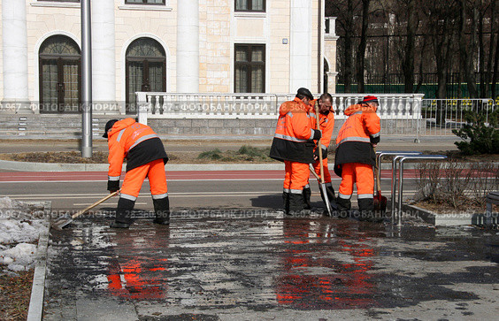 Несколько рабочих в оранжевой спецодежде убирают снег и лед. Город Москва, Лужнецкая набережная, апрель (2018 год). Редакционное фото, фотограф Щеголева Ольга / Фотобанк Лори