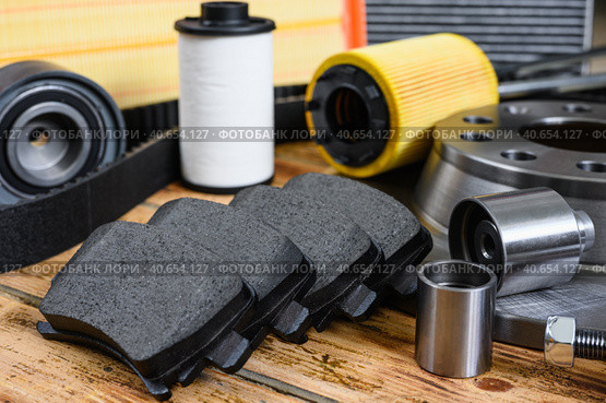 New car parts on a wooden table. Selective focus on brake pads. Car maintenance and repair concept. Стоковое фото, фотограф Никита Бурденков / Фотобанк Лори