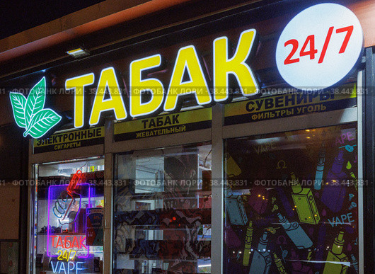 Ночная светящаяся вывеска "Табак 24/7" над зоной курения и круглосуточным киоском продаж (2022 год). Редакционное фото, фотограф Grigory_Gez / Фотобанк Лори