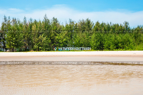 Nopparat Thara Beach in Ao Nang, Krabi Province, Thailand. A line of green trees with a signboard announcing the name of the white sand beach. Стоковое фото, фотограф Коханова Наталья / Фотобанк Лори