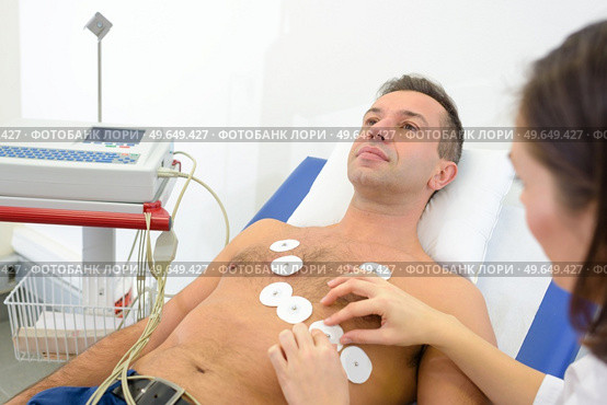 Nurse attaching heart monitor pads to man's chest. Стоковое фото, агентство Ingram Publishing / Фотобанк Лори