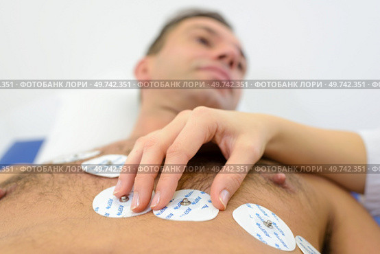 nurse sticking holter on patients chest in hospital. Стоковое фото, агентство Ingram Publishing / Фотобанк Лори
