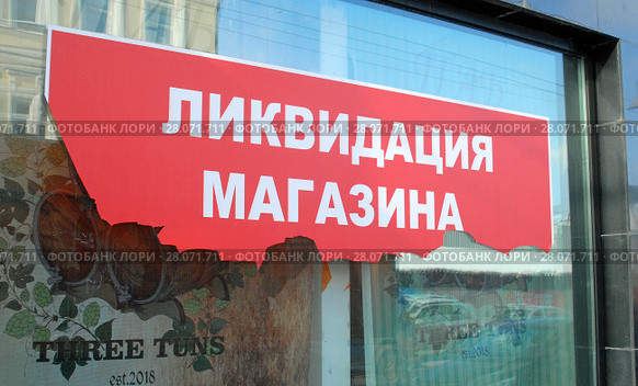Оборванная вывеска "Ликвидация магазина" на уличной витрине (2018 год). Редакционное фото, фотограф Александр Замараев / Фотобанк Лори