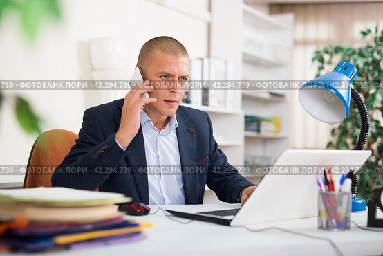 Office man is discussing the contract by phone in office. Стоковое фото, фотограф Яков Филимонов / Фотобанк Лори