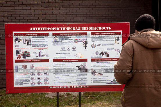 Охранник читает информацию у стенда по антитеррористической безопасности в Парке Горького в городе Москве, Россия (2023 год). Редакционное фото, фотограф Николай Винокуров / Фотобанк Лори