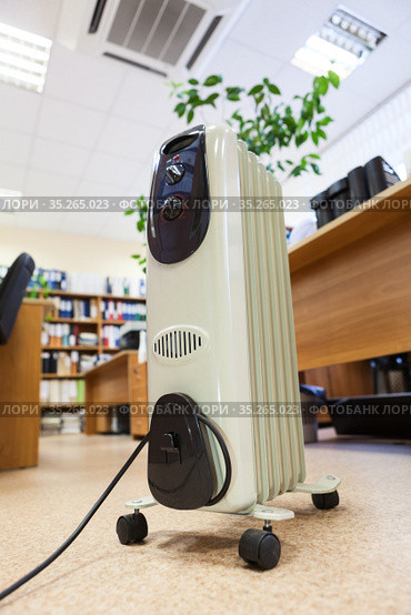 Oil electric radiator using in office, unit standing in center of the room. Стоковое фото, фотограф Кекяляйнен Андрей / Фотобанк Лори