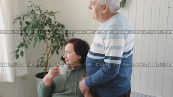 Old couple have breakfast sitting at the kitchen table, drink coffee. Embracing elderly man and woman. Senior couple together marriage in retirement talking with each other. Enjoying the pleasantries. Стоковое видео, видеограф Марина Демидюк / Фотобанк Лори